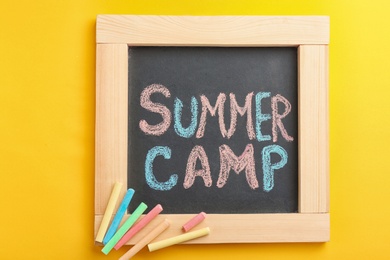 Photo of Text "SUMMER CAMP" on small blackboard and colorful chalk, top view