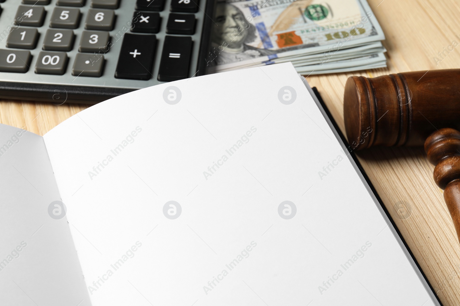 Photo of Tax law. Notebook, gavel, dollar banknotes and calculator on wooden table, closeup