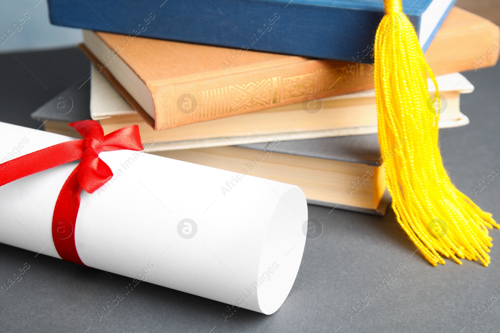 Photo of Graduation hat, books and student's diploma on grey table, closeup