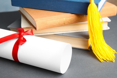 Photo of Graduation hat, books and student's diploma on grey table, closeup