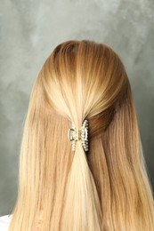 Young woman with beautiful hair claw on grey background, back view