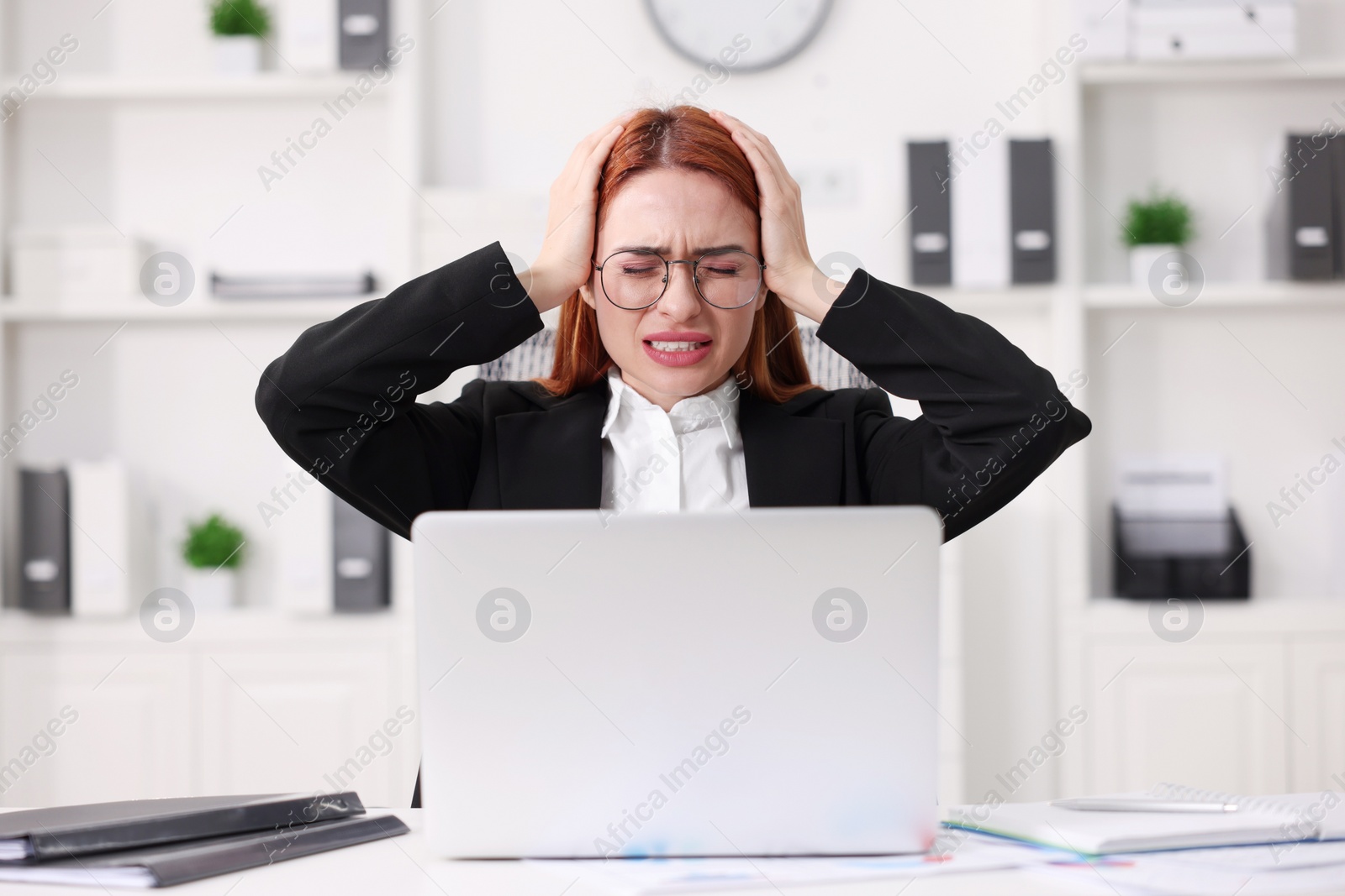 Photo of Woman suffering from headache at workplace in office