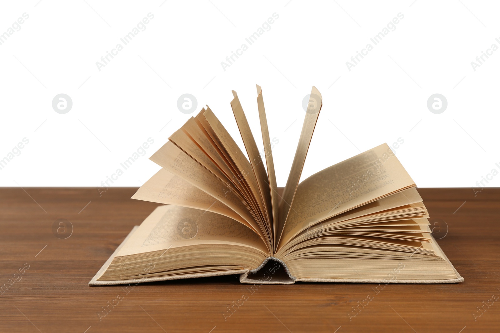 Photo of Open book on wooden table against white background. Library material