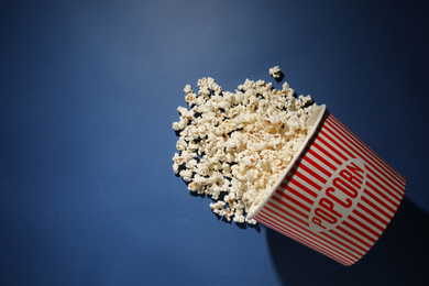 Photo of Delicious popcorn on blue background, top view. Space for text