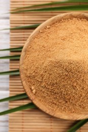 Photo of Coconut sugar, palm leaves and bamboo mat on table, top view