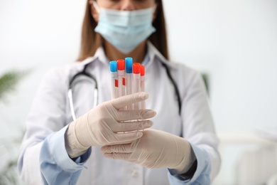 Photo of Doctor holding tubes with cotton swabs for DNA test in clinic, closeup