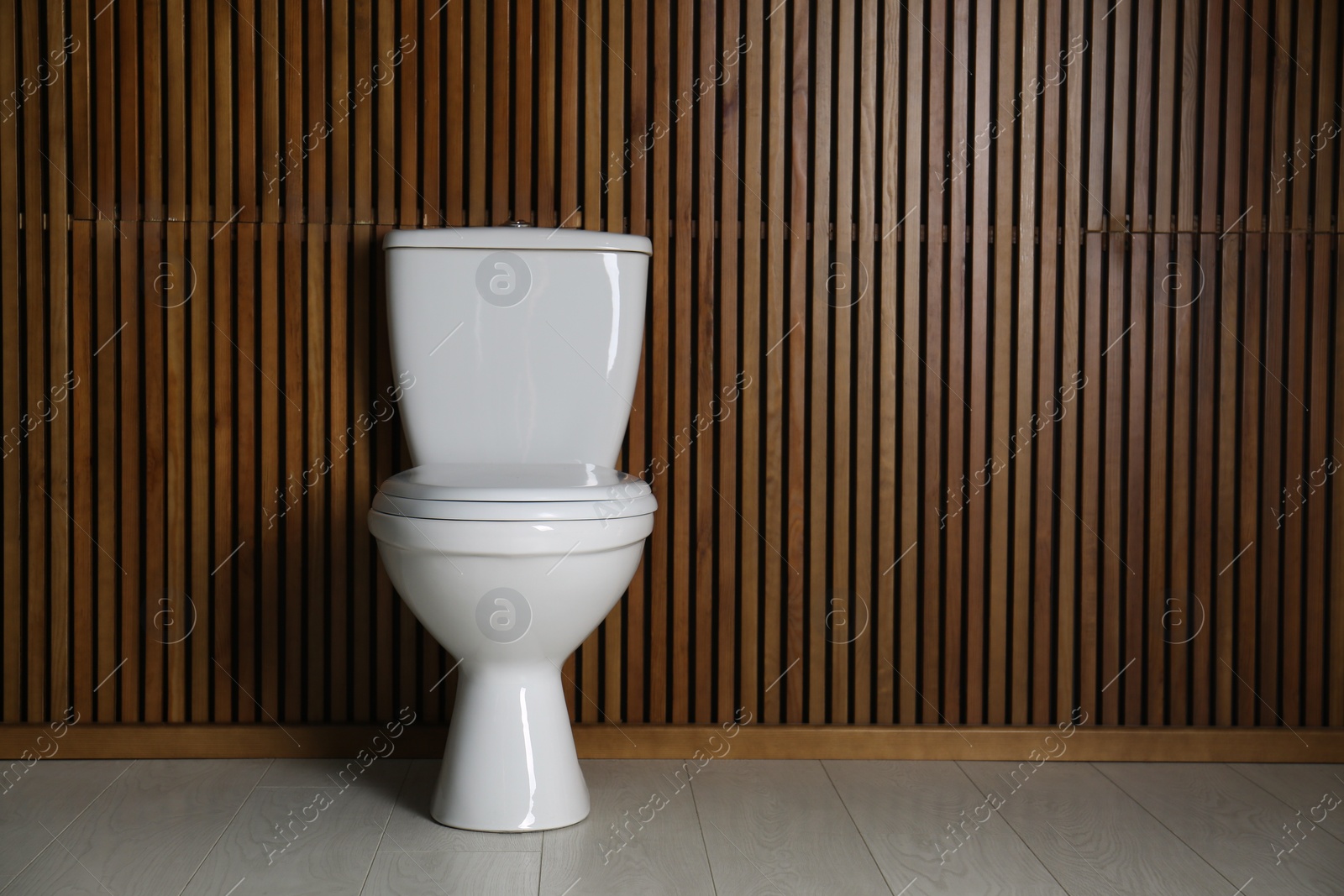 Photo of New toilet bowl near wooden wall indoors. Space for text