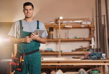 Photo of Professional carpenter with tablet in modern workshop