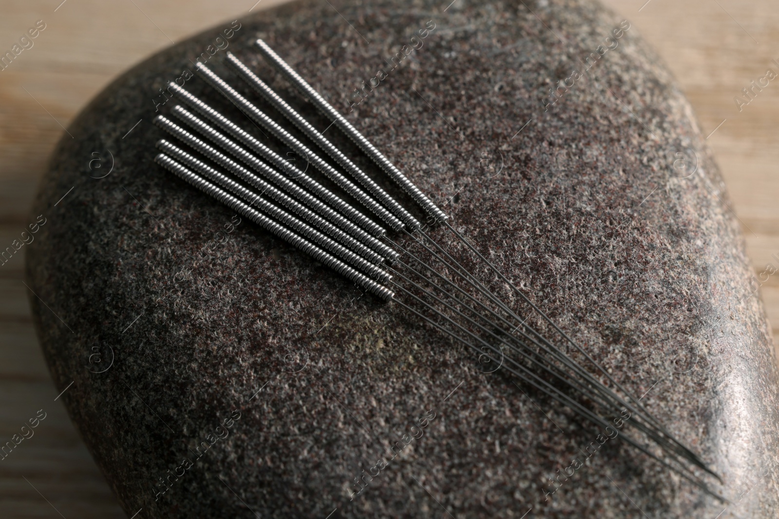 Photo of Acupuncture needles and spa stone on table, closeup