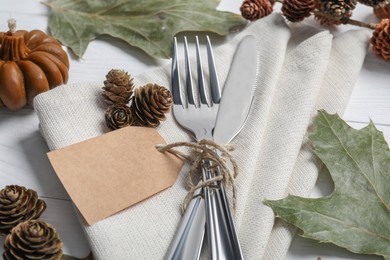 Photo of Thanksgiving day table setting. Cutlery, napkin and autumn decoration on white wooden background, closeup