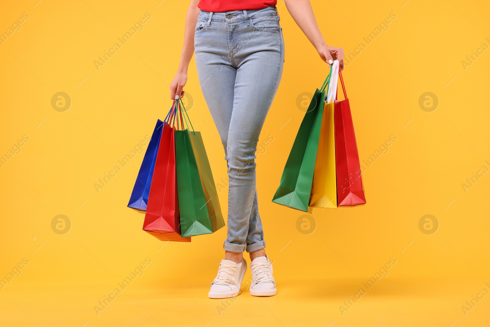 Photo of Woman with shopping bags on yellow background, closeup