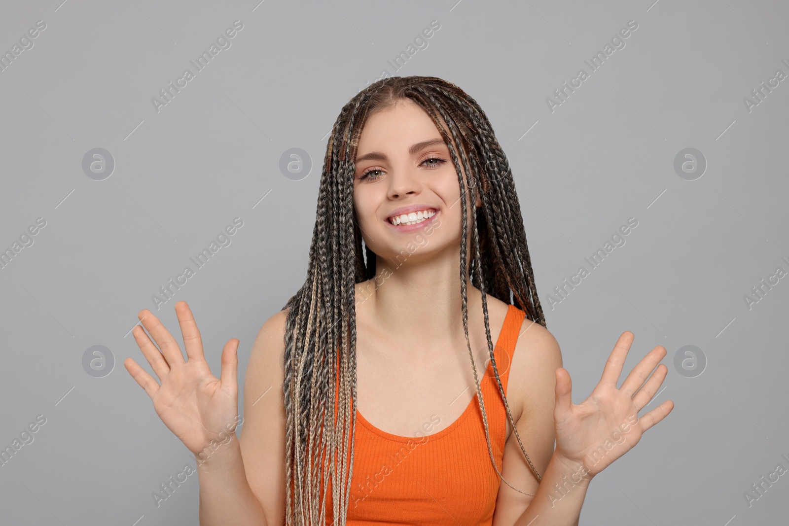 Photo of Young woman giving high five with both hands on grey background