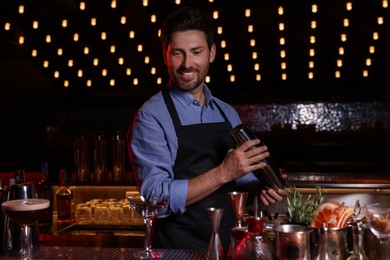 Photo of Bartender with shaker preparing fresh alcoholic cocktail in bar