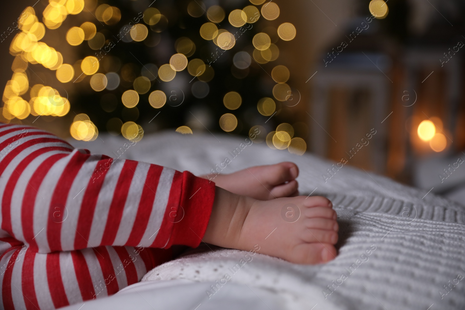 Photo of Baby in Christmas pajamas sleeping on bed indoors, closeup