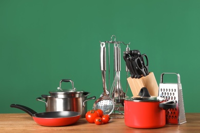 Photo of Set of clean cookware and utensils on table against color background