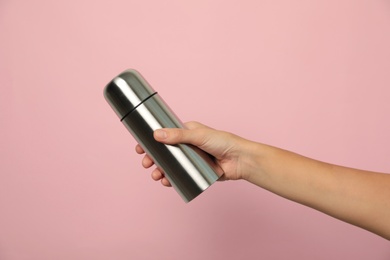 Woman holding modern thermos on pink background, closeup
