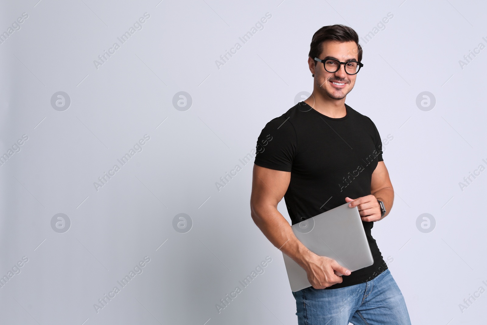 Photo of Handsome young man with laptop on grey background. Space for text