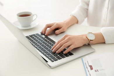 Young businesswoman using laptop at table in office, closeup