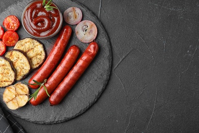 Flat lay composition with delicious grilled sausages on black table, space for text. Barbecue food