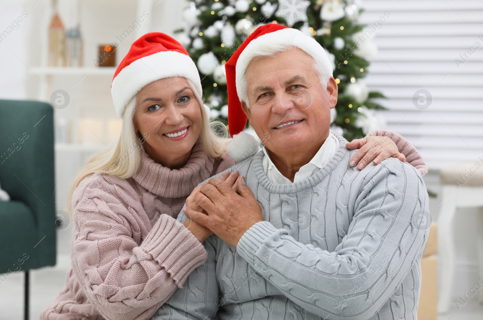 Photo of Happy mature couple in Santa hats at home. Christmas celebration