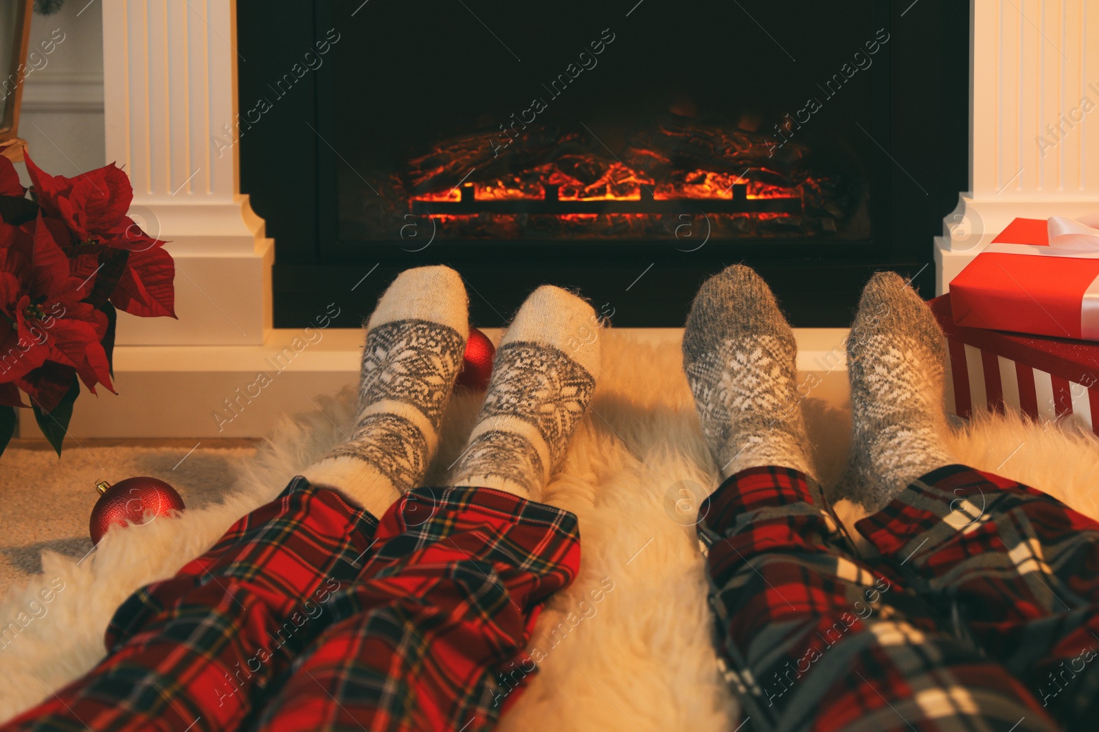 Photo of Couple in warm socks resting near fireplace at home, closeup