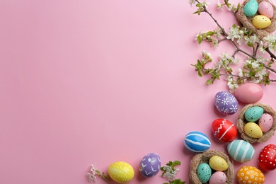 Photo of Flat lay composition with painted Easter eggs and blossoming branches on color background, space for text