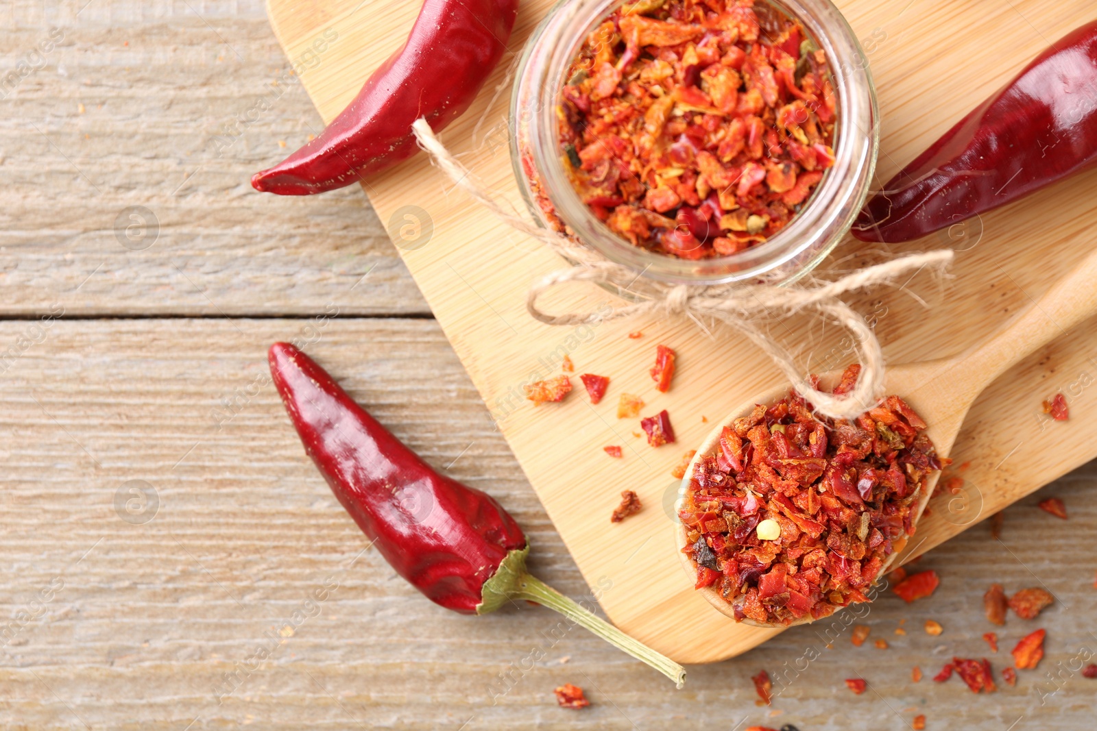 Photo of Chili pepper flakes and pods on wooden table, top view