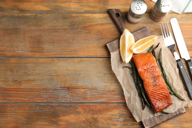 Tasty cooked salmon and vegetables served on wooden table, flat lay with space for text. Healthy meals from air fryer