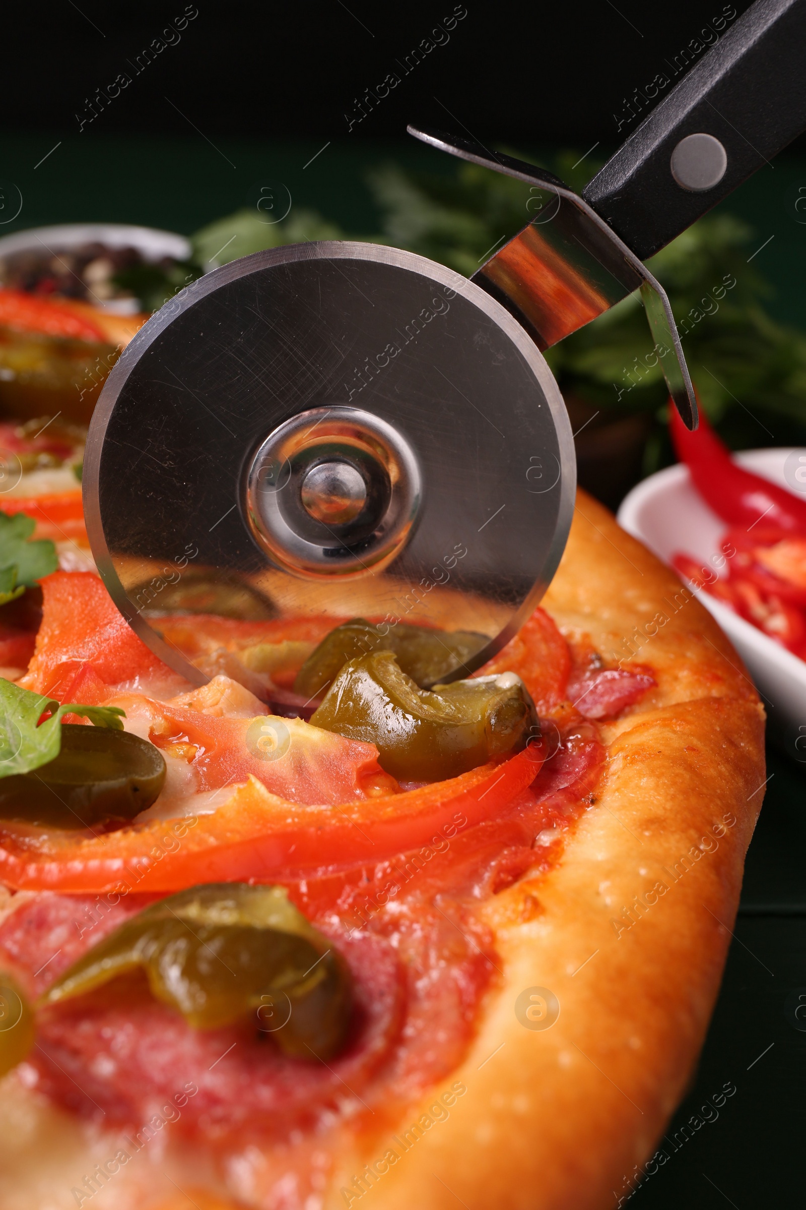 Photo of Cutting delicious pizza Diablo at table, closeup