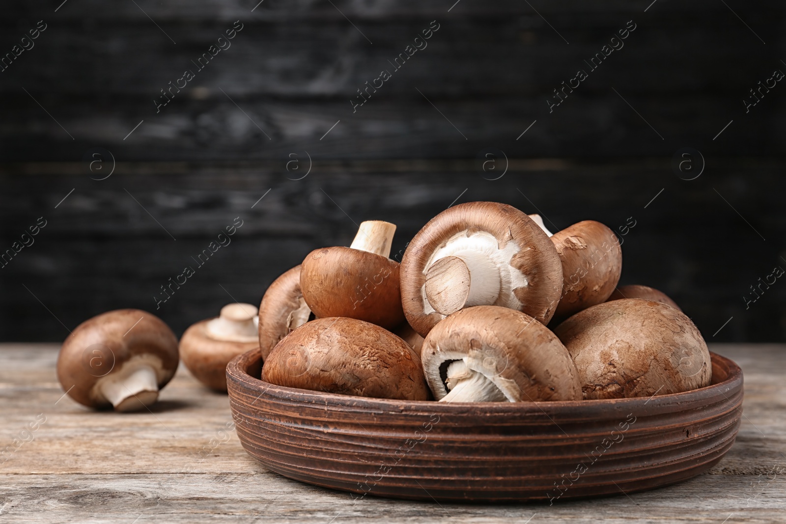 Photo of Bowl of fresh champignon mushrooms on table against black background. Space for text