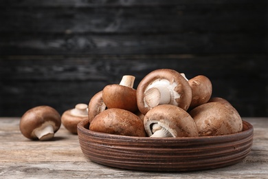 Bowl of fresh champignon mushrooms on table against black background. Space for text