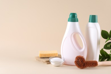 Photo of Bottles of cleaning product, sponges, brush and baking soda on beige background. Space for text