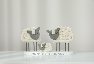 Cute decorative sheep and lamb figurine with phrase Dream Big Little One on white table against light background. Family Day