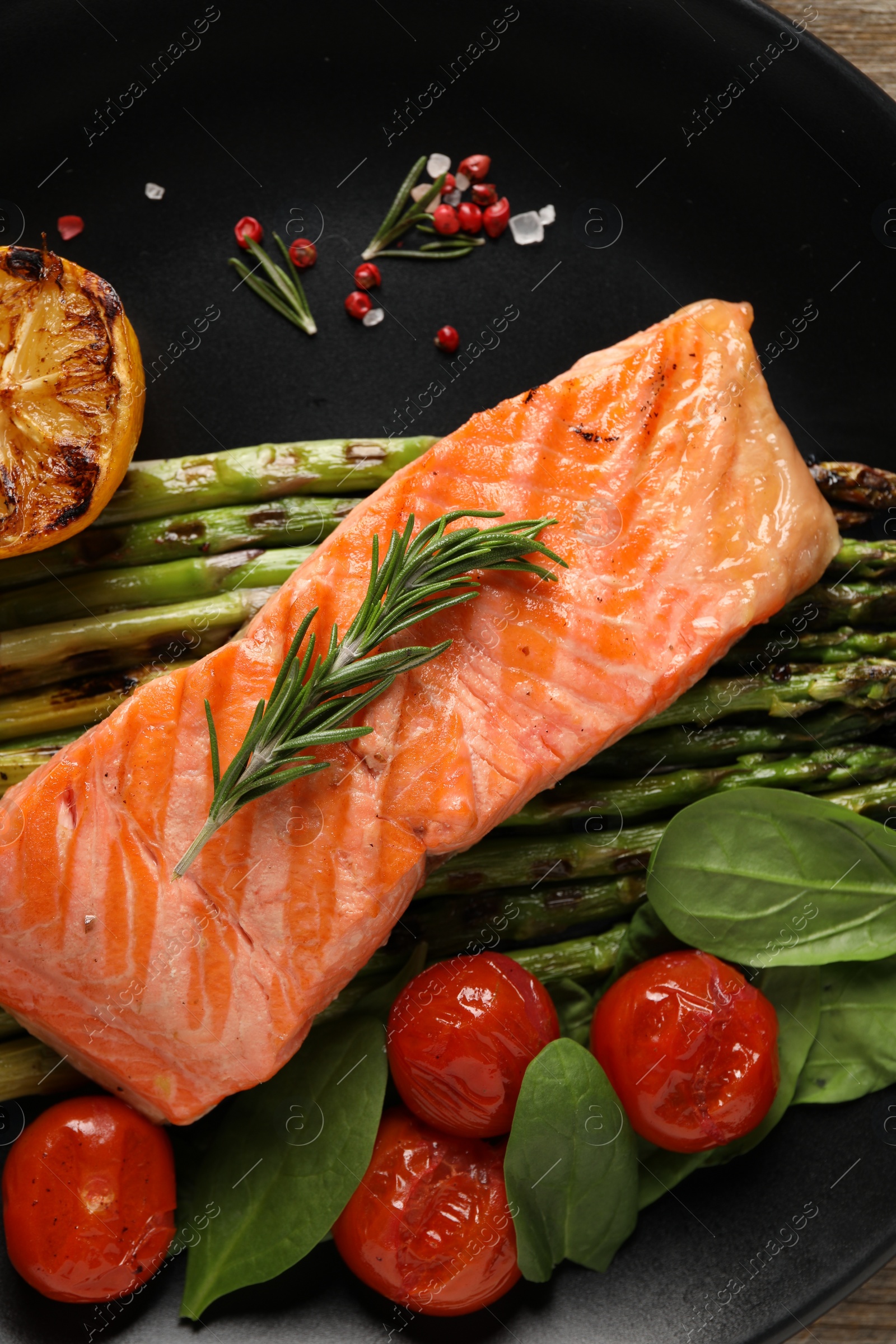 Photo of Tasty grilled salmon with tomatoes, asparagus and spices on plate, top view