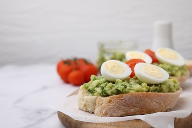 Delicious sandwiches with guacamole, eggs and tomatoes on white table, closeup