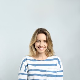 Photo of Portrait of happy young woman with beautiful blonde hair and charming smile on light background