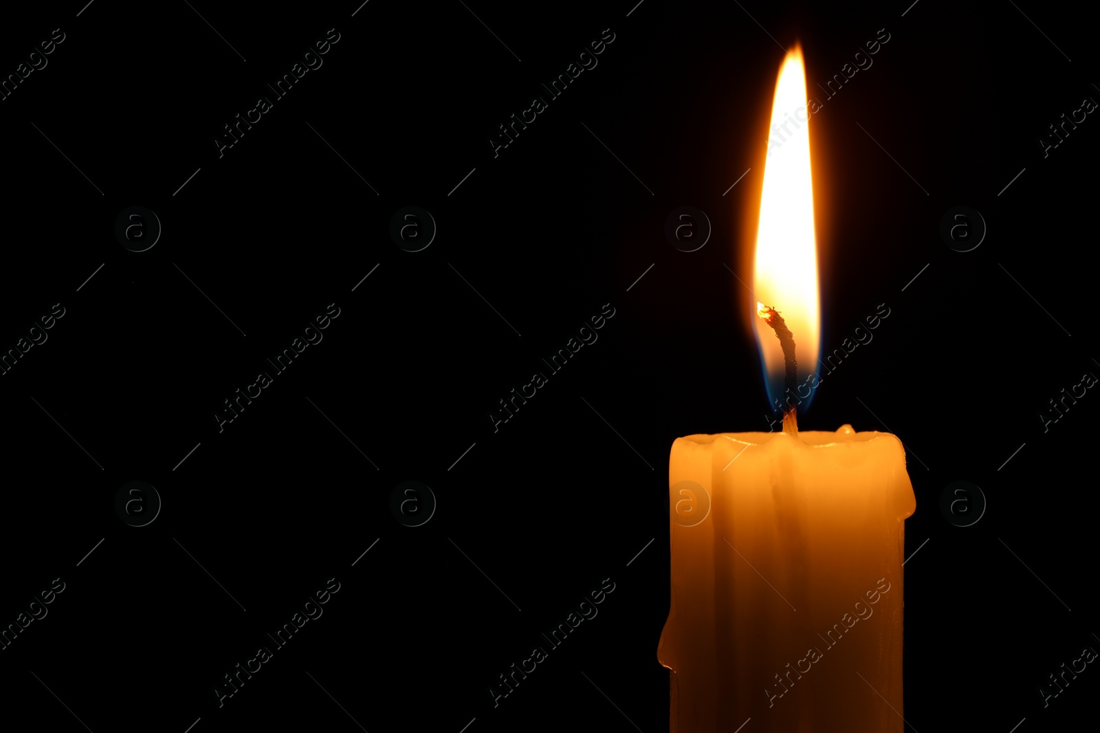 Photo of Burning candle on black background, closeup. Space for text