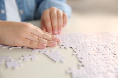 Photo of Little girl playing with puzzles at table, closeup