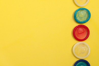Condoms on yellow background, top view with space for text. Safe sex