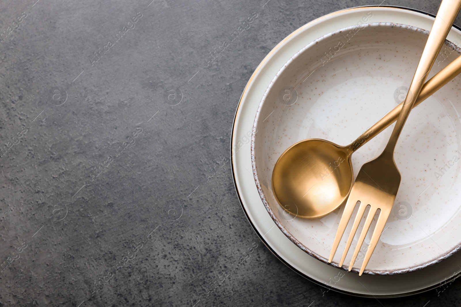 Photo of Stylish empty dishware and cutlery on grey table, top view. Space for text