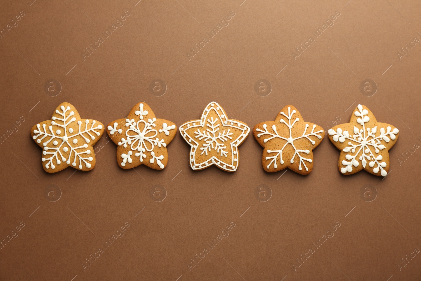 Photo of Tasty Christmas cookies with icing on brown background, flat lay