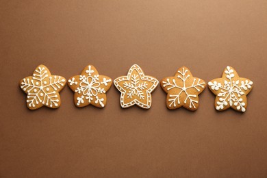 Photo of Tasty Christmas cookies with icing on brown background, flat lay