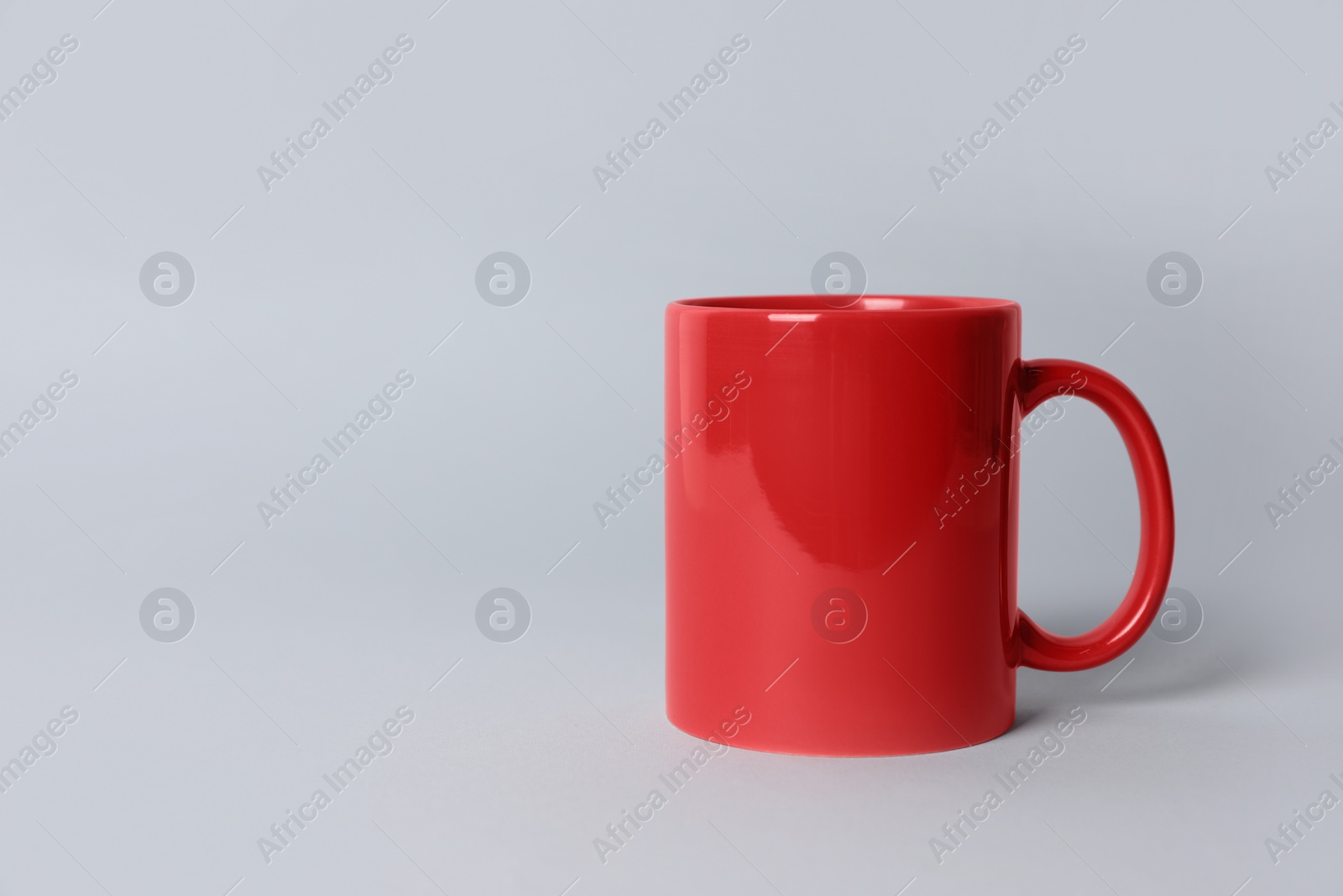 Red ceramic mug on light grey background. Space for text Photo of Red ceramic mug on light grey background. Space for text