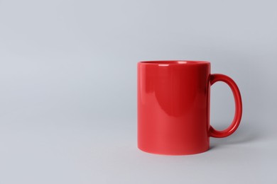 Photo of Red ceramic mug on light grey background. Space for text