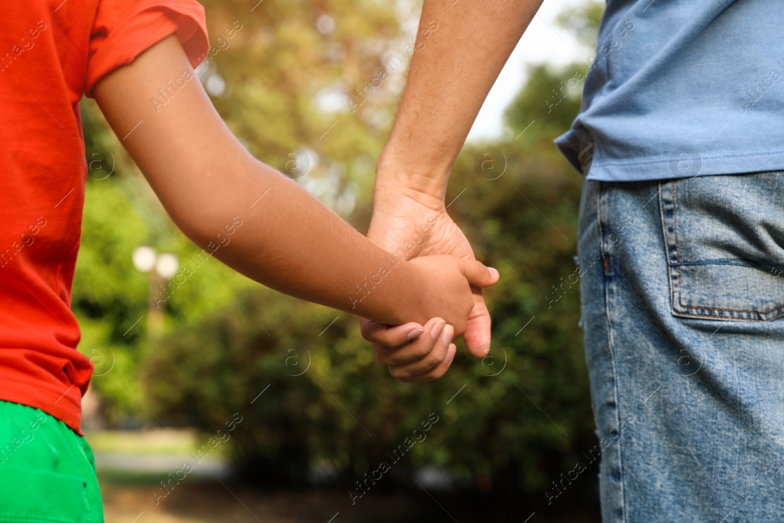 Photo of Little boy and his father holding hands outdoors, closeup. Family weekend