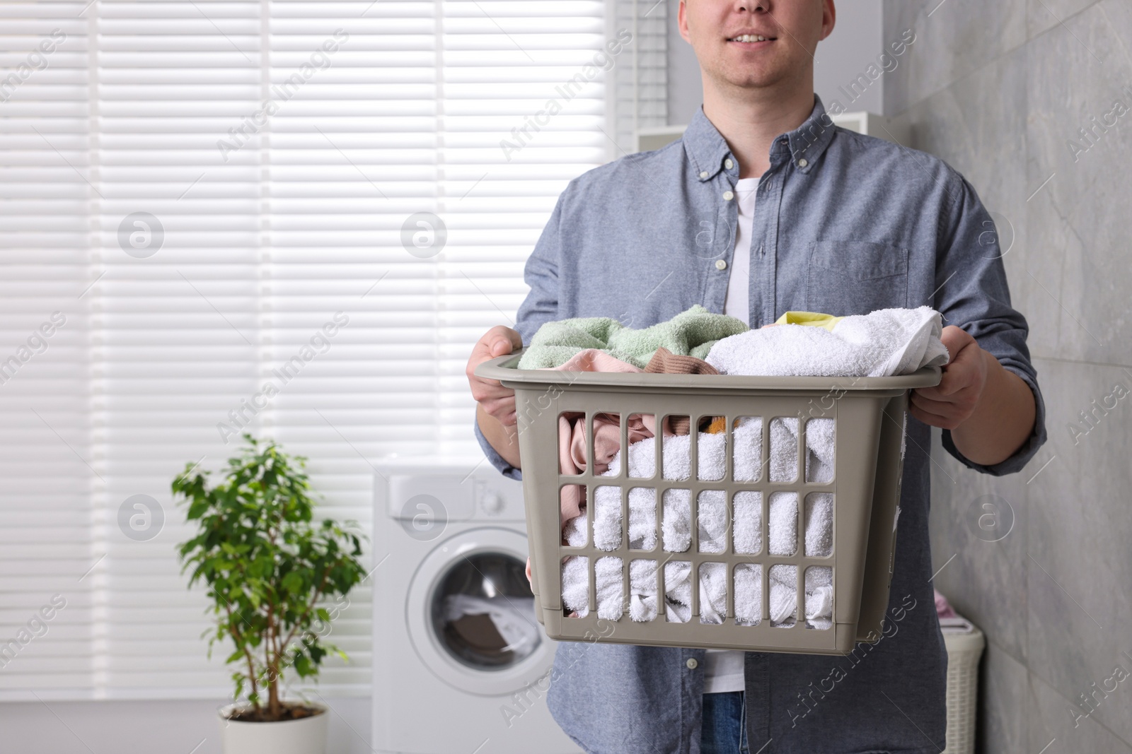 Photo of Man with basket full of laundry in bathroom, closeup