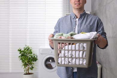 Photo of Man with basket full of laundry in bathroom, closeup