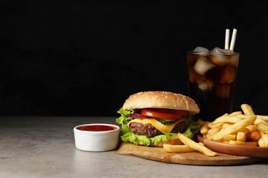 Delicious burger, soda drink and french fries served on grey table. Space for text