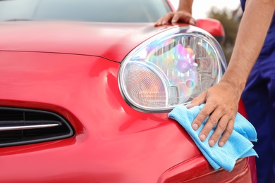 Photo of Man cleaning red auto with duster, closeup. Car wash service