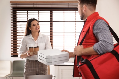 Courier giving order to young woman in office. Food delivery service